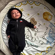 Dameon joined the competition — help win amazing prizes! baby, infant, black_clothing, nike, onesie, monthly_milestone, blanket, elephant, numbers, flooring, wood_floor, cute, child, face, portrait, lying_down, soft_toy, home, indoor, smile