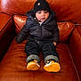 Levi is registered to the contest to win money with this photo: toddler, child, sitting, jacket, beanie, shoes, sneakers, couch, leather, brown, clothing, pants, indoor, person, cute, young_child, warm_clothing, footwear, casual, portrait