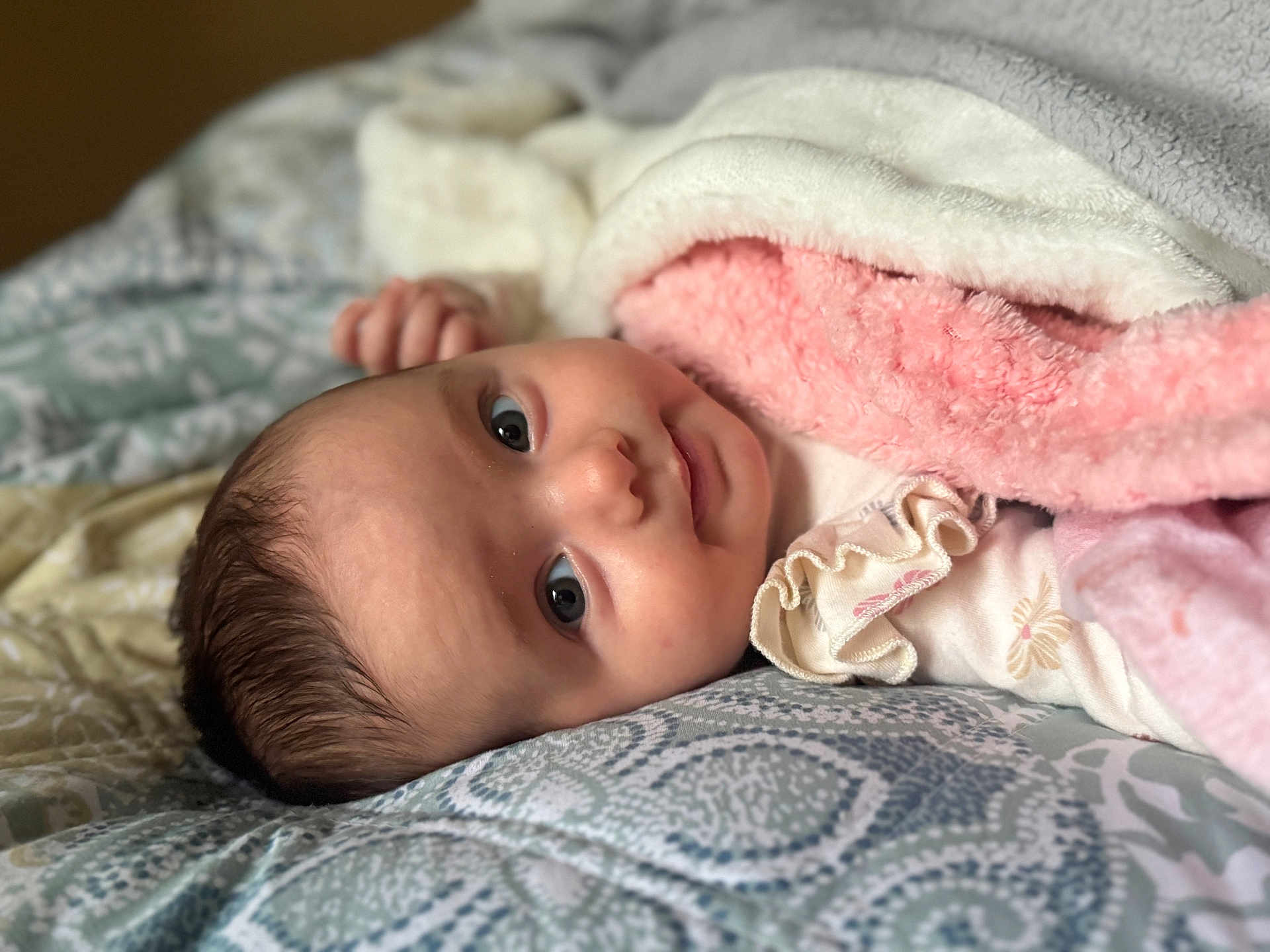 Zlata is registered to the contest to win money with this photo: baby, bed, blanket, clothing, comfort, cozy, cute, expression, face, head, indoors, infant, lying_down, pattern, skin, sleepwear, smile, soft, warm, young_child