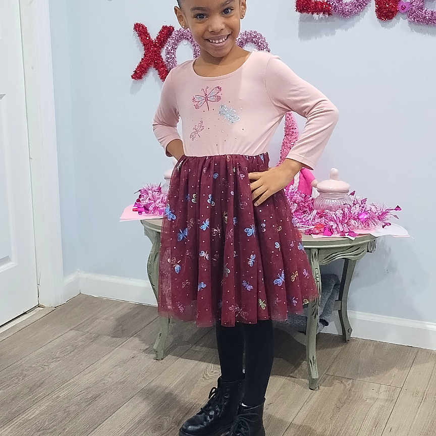 Melody is registered to the contest to win money with this photo: child, clothing, costume, dress, face, female, footwear, girl, hardwood, head, pants, person, photography, plant, portrait, pottedplant, purple, shoe, skirt, wood