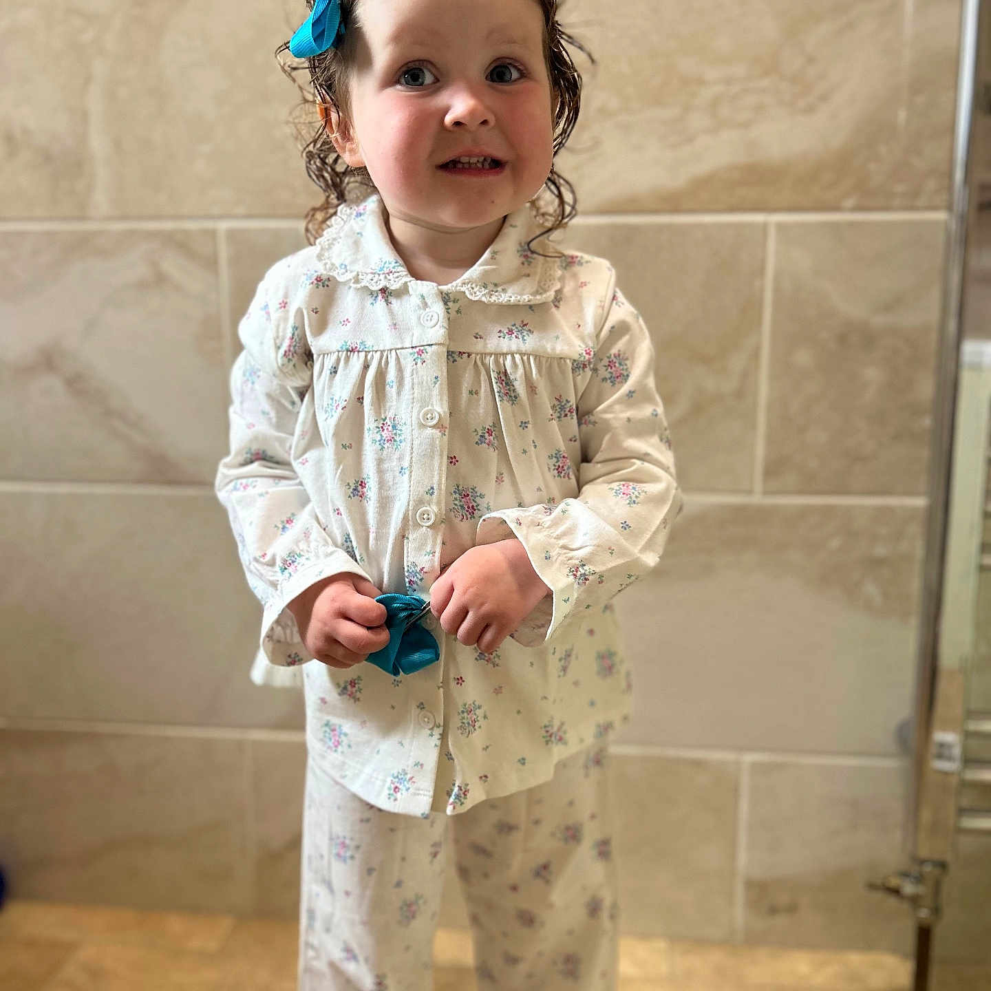 Elbee-Rain is registered to the contest to win money with this photo: bathroom, bedtime, blue_bow, child, clothing, curly_hair, cute, fashion, floor, holding, indoor, pajamas, person, portrait, small_hands, smiling, standing, tile_wall, toddler, young_child