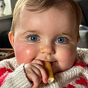 Ambre a rejoint le concours — aidez-le/la à gagner de superbes lots ! baby, face, blue_eyes, cheeks, hand, biscuit, sweater, red_hearts, knitted, closeup, cute, child, indoor, person, skin, fingernails, warm, cozy, expression, happy