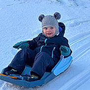 Ayden a rejoint le concours — aidez-le/la à gagner de superbes lots ! child, toddler, sled, snow, winter_clothing, hat, gloves, outdoor, play, happy, smile, cold_weather, recreation, snow_sledding, winter_fun, blue_sled, snow_tracks, young_child, park, active