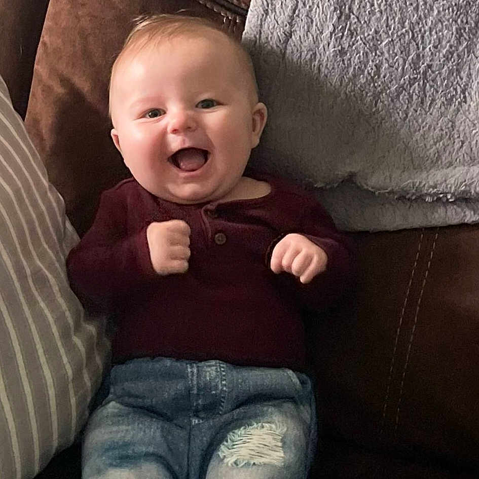 Grayson joined the competition — help win amazing prizes! baby, child, couch, cozy, cute, furniture, gray_blanket, happy, indoor, infant, jeans, leather_couch, maroon_sweater, pillow, portrait, ripped_jeans, sitting, smiling, striped_pillow, young_child