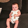 Elliana is registered to the contest to win money with this photo: baby, barefoot, child, clothing, comfortable, couch, cute, expression, face, furniture, home, indoors, infant, person, rainbow_pattern, romper, sitting, skin, sofa, young_child