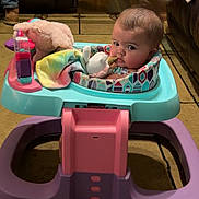 Elliana joined the competition — help win amazing prizes! baby, blanket, carpet, child, colorful, couch, curious, face, floor, footwear, furniture, head, indoor, living_room, person, plush_toy, seated, socks, toy, walker