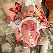 Renee-Rose joined the competition — help win amazing prizes! baby, infant, smiling, headband, bow, pink_outfit, white_socks, cushion, butterfly, plush_toy, bed, blanket, cute, child, portrait, happy, indoor, clothing, fabric, person