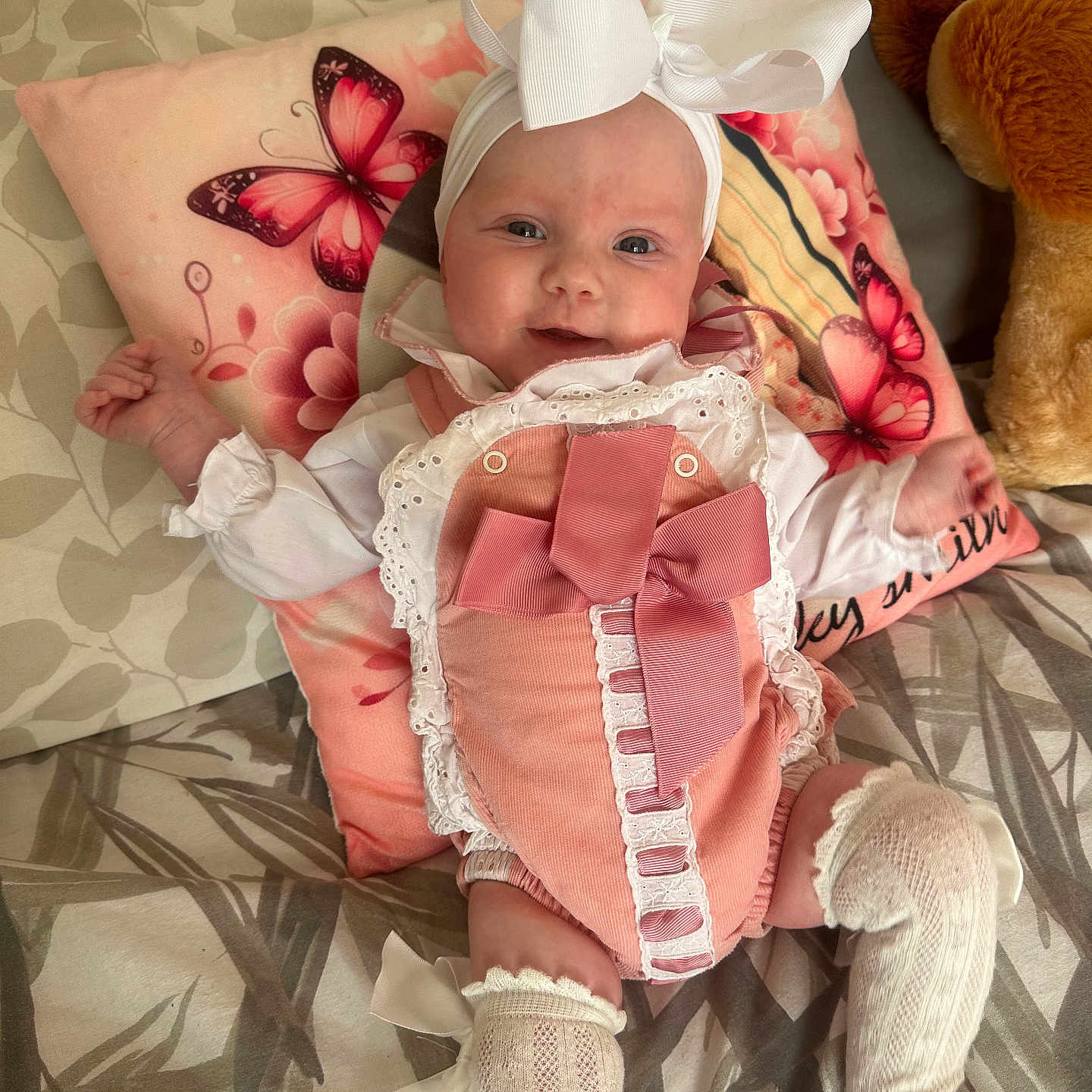 Renee-Rose joined the competition — help win amazing prizes! baby, bed, blanket, bow, butterfly, child, clothing, cushion, cute, fabric, happy, headband, indoor, infant, person, pink_outfit, plush_toy, portrait, smiling, white_socks