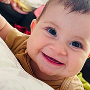 Eveline participe au concours pour gagner de l'argent avec cette photo : baby, smiling, close_up, face, child, infant, happy, eyes, skin, mouth, teeth, clothing, head, indoors, soft_surface, blanket, cushion, person, cute, portrait