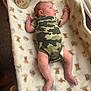 Theodore joined the competition — help win amazing prizes! baby, infant, onesie, camouflage, blanket, teddy_bear_pattern, bassinet, wooden_sign, one_month, carpet, sunlight, indoor, newborn, sleeping_area, cute, small, person, child, lying_down, cozy