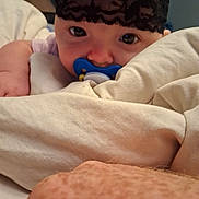 Rebel is registered to the contest to win money with this photo: baby, pacifier, blanket, face, headband, arm, skin, bed, sleepwear, closeup, indoor, infant, person, cute, rest, comfort, soft, expression, young, lying