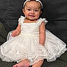 baby, child, dress, white_dress, headband, smile, sitting, couch, indoor, cute, infant, portrait, happy, barefoot, young_child, girl, fabric, lace, person, clothing