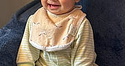 Luna is registered to the contest to win money with this photo: baby, child, smiling, pajamas, bib, blue_blanket, indoor, sitting, cute, happy, face, person, infant, young, cozy, soft_lighting, portrait, hands, footed_pajamas, home