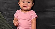 Luna is registered to the contest to win money with this photo: arm, baby, child, couch, cute, fabric, face, furniture, happy, home, indoor, infant, person, pink_onesie, portrait, sitting, skin, smiling, texture, young_child