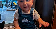 Laios joined the competition — help win amazing prizes! toddler, child, denim_overall, dinosaur, toy_vehicle, indoor, home, wooden_floor, glass_door, backyard, furniture, curtain, footwear, person, baby, face, hand, play, smile, motion_blur