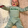 baby, child, face_paint, striped_clothing, green, lying_down, rug, happy, smiling, infant, toddler, cute, indoors, cozy, young_child, clothing_text, long_sleeves, pajamas, feet, portrait