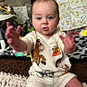 Jackson is registered to the contest to win money with this photo: baby, child, toy_story, clothing, indoor, blanket, carpet, person, face, hand, expression, cute, playful, colorful, room, furniture, sitting, soft, young_child, reaching