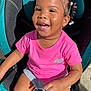 toddler, child, smiling, car_seat, braided_hair, beads, pink_shirt, shorts, sunlight, happy, outdoor, seat, person, cute, portrait, young_child, fashion, casual, joy, daylight