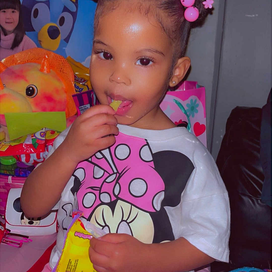 Stormi Lynn Punter is registered to the contest to win money with this photo: child, tiara, snack, pink_pants, minnie_mouse_shirt, toys, indoor, cute, smiling, young_child, colorful, playful, hair_buns, jewelry, earrings, sitting, happy, portrait, celebration, fun
