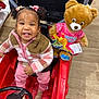 Stormi Lynn Punter joined the competition — help win amazing prizes! toddler, child, toy_car, red, teddy_bear, stuffed_animal, happy_birthday, pink_clothing, hair_bows, curly_hair, striped_jacket, indoor, floor, wooden_floor, shopping_store, seat, steering_wheel, cute_expression, plush_toy, colorful_clothing
