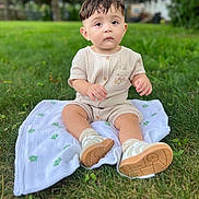 Noah Jose Galeano is registered to the contest to win money with this photo: baby, child, infant, grass, outdoor, blanket, shoes, romper, greenery, nature, cute, portrait, sitting, young_child, footwear, expression, daylight, soft_texture, casual_clothing, curious