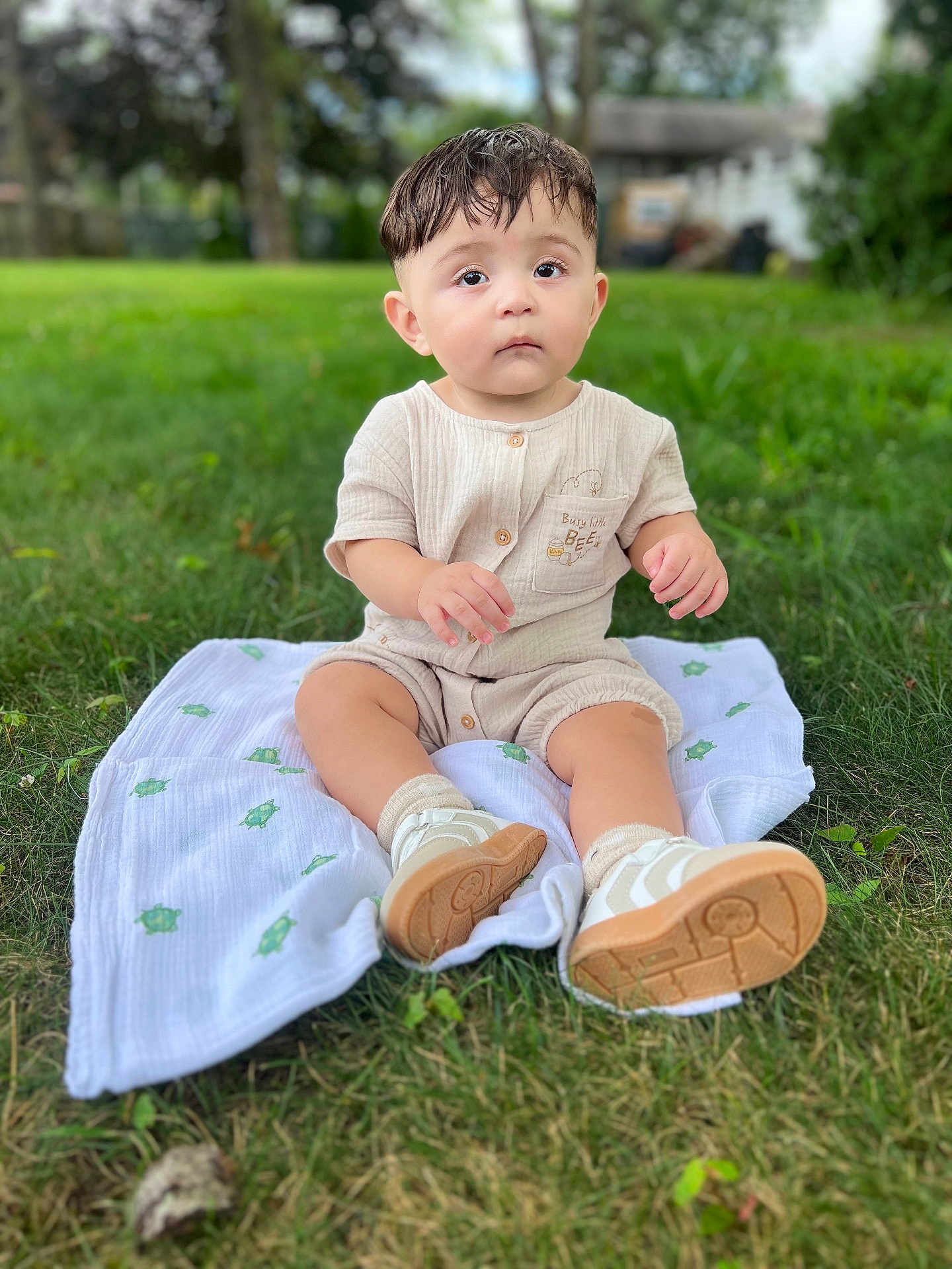 Noah Jose Galeano is registered to the contest to win money with this photo: baby, child, infant, grass, outdoor, blanket, shoes, romper, greenery, nature, cute, portrait, sitting, young_child, footwear, expression, daylight, soft_texture, casual_clothing, curious