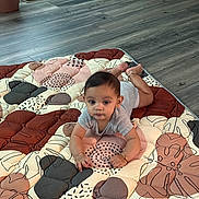 Vishruth joined the competition — help win amazing prizes! baby, child, indoor, quilt, flooring, pattern, curious, lying_down, clothing, bracelet, infant, person, home, wood_floor, decoration, mat, baby_girl, baby_boy, cute, portrait