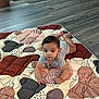 baby, child, indoor, quilt, flooring, pattern, curious, lying_down, clothing, bracelet, infant, person, home, wood_floor, decoration, mat, baby_girl, baby_boy, cute, portrait