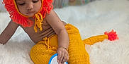 Vishruth is registered to the contest to win money with this photo: baby, infant, child, knitted_clothing, lion_hat, yellow, orange, plush_rug, card, months, indoor, playpen, animal_prints, cute, sitting, portrait, young_child, soft_texture, hand, feet