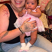 Mckenna Brook joined the competition — help win amazing prizes! woman, baby, infant, tattoo, smile, holding, pink_dress, socks, indoor, bed, pillow, person, toddler, happy, casual, hair, face, jeans, hand, candid