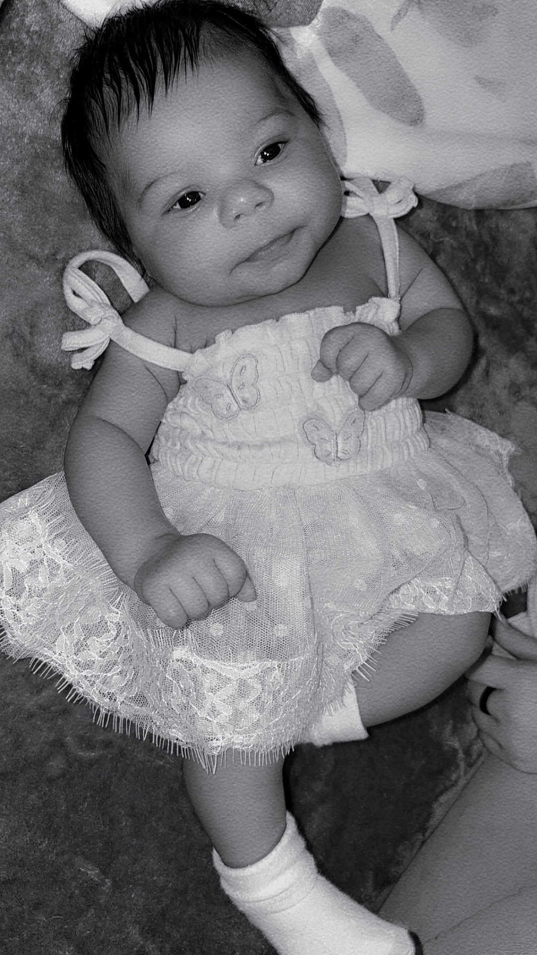 Mckenna Brook is registered to the contest to win money with this photo: baby, infant, dress, lace, butterfly, sock, cute, child, portrait, black_and_white, soft_texture, smile, person, newborn, clothing, lying_down, hand, foot, face, young