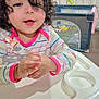 toddler, child, high_chair, curly_hair, striped_shirt, indoor, playpen, toy, baby, person, happy, smiling, face, table, furniture, curly, cute, infant, clothing, hands