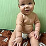 baby, infant, child, diaper, bare_skin, sitting, blanket, brown_blanket, hand, foot, face, curly_hair, cute, chubby, expression, indoors, green_wall, soft_light, portrait, candid