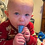 Kayden joined the competition — help win amazing prizes! toddler, child, pajamas, indoors, freeze_pop, hand, face, blue, red, toy, furniture, curious, closeup, person, chewing, baby, comfort, warm_clothing, cute, expression