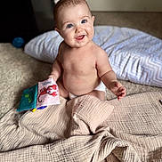 Hailey joined the competition — help win amazing prizes! baby, child, smiling, blue_eyes, diaper, fabric_book, lobster_cartoon, quilt, beige, carpet, pillow, indoor, cute, happy, sitting, infant, playful, soft_light, portrait, person