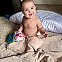 baby, child, smiling, blue_eyes, diaper, fabric_book, lobster_cartoon, quilt, beige, carpet, pillow, indoor, cute, happy, sitting, infant, playful, soft_light, portrait, person