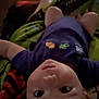 baby, child, infant, face, eyes, legs, shirt, animal_print, lying_down, indoor, low_light, blur, person, clothing, skin, foot, casual, expression, portrait, childrenswear