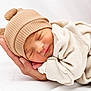 newborn, baby, sleeping, hat, knit_hat, beige, blanket, wrapped, hand, adult_hand, soft, cozy, peaceful, portrait, closeup, indoor, cute, infant, resting, toddler