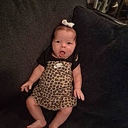 Reyna is registered to the contest to win money with this photo: baby, infant, child, couch, clothing, leopard_print, nike, bow, sitting, expression, face, indoors, furniture, person, footwear, cute, skin, legs, hand, headwear