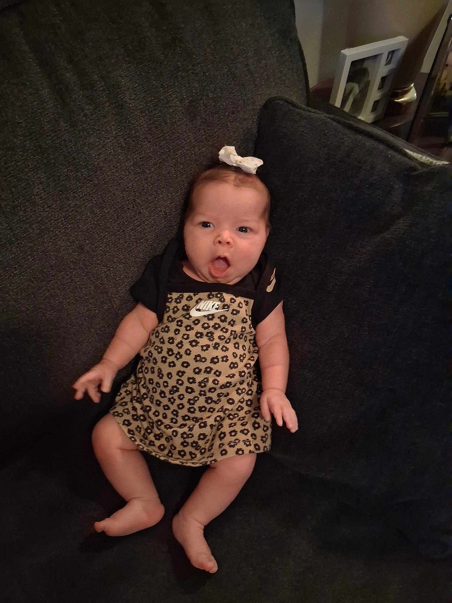Reyna is registered to the contest to win money with this photo: baby, infant, child, couch, clothing, leopard_print, nike, bow, sitting, expression, face, indoors, furniture, person, footwear, cute, skin, legs, hand, headwear