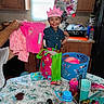 Camilla joined the competition — help win amazing prizes! balloon, birthday_crown, cabinet, celebration, child, cup, cupcake, gift_bag, happy, holding, indoor, kitchen, party, person, pink_clothing, refrigerator, smile, snack, table, water_bottle