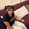 Camilla is registered to the contest to win money with this photo: black_shirt, braided_hair, casual, couch, furniture, girl, hair, happy, home, indoor, person, pigtails, pillow, relaxed, resting, seated, sitting, smile, white_pants, young