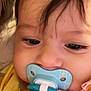 baby, pacifier, face, child, yellow_clothing, closeup, infant, skin, hair, eyes, mouth, cute, young, indoors, person, portrait, childhood, baby_girl, baby_boy, calm