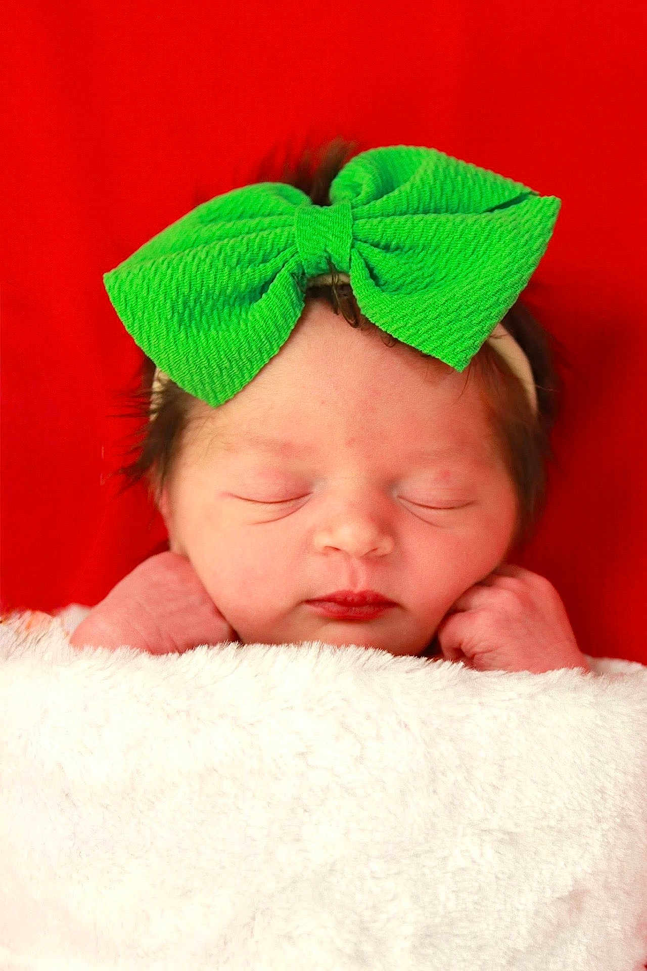 Josette joined the competition — help win amazing prizes! newborn, baby, infant, sleeping, green_bow, headband, blanket, white_blanket, red_background, face, peaceful, cute, wrapped, portrait, closeup, soft_texture, skin, tiny_hands, resting, indoors