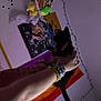 Nova is registered to the contest to win money with this photo: arm, bed_frame, bedroom, black_cat, bracelets, colorful, decor, hand, indoor, kitten, night, person, plush_toys, poster, rainbow_flag, scooter, string_lights, stuffed_animals, toy_storage, wall