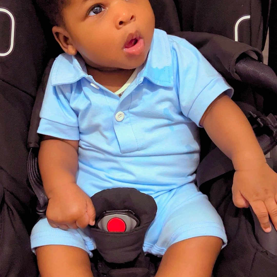 Shaun Leeroy Andrew a rejoint le concours — aidez-le/la à gagner de superbes lots ! baby, black_car_seat, blue_clothing, car_seat, child, clothing, curious, cute, expression, face, hand, indoor, infant, person, portrait, seat_belt, sitting, socks, toddler, young_child