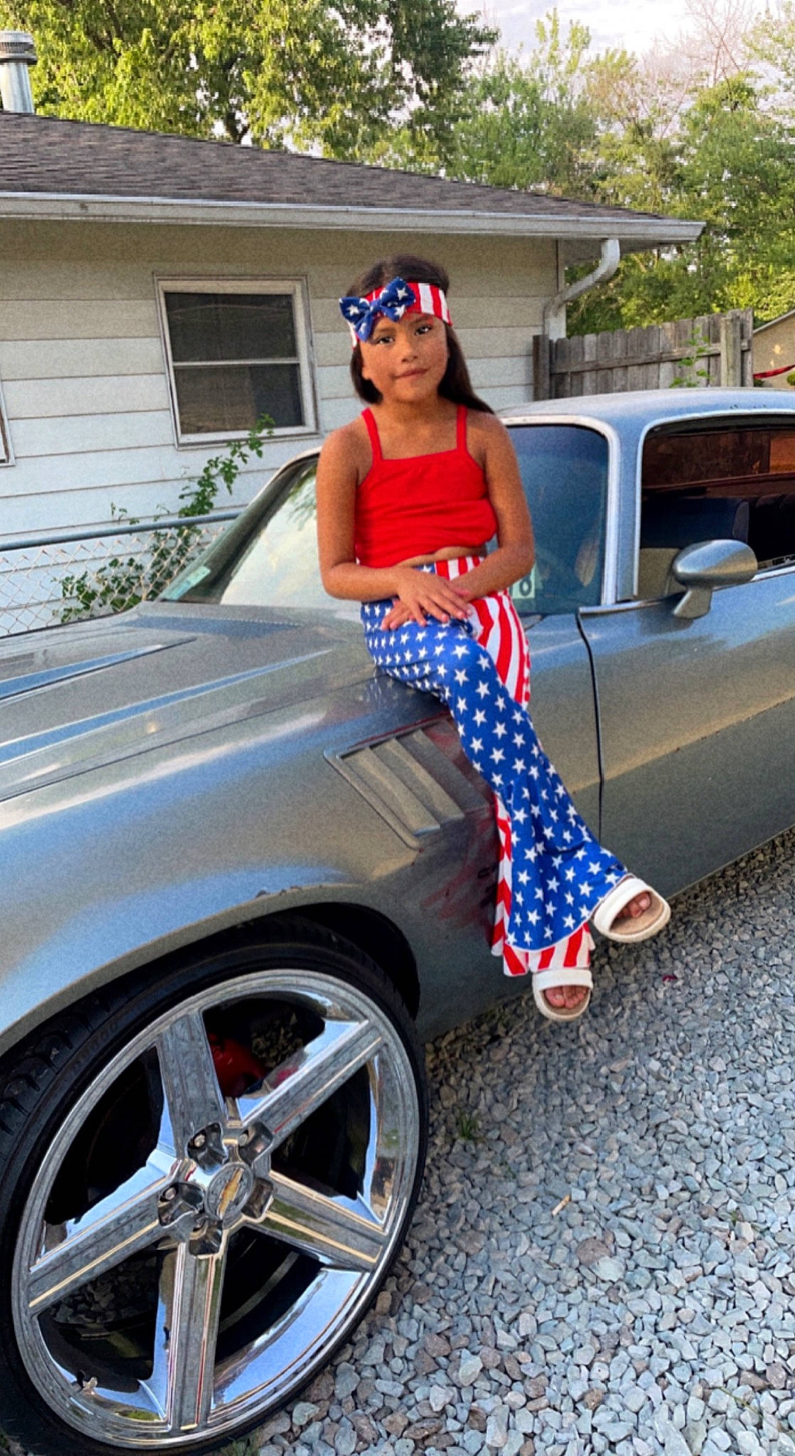 Mia is registered to the contest to win money with this photo: alloy_wheel, automotive_design, automotive_exterior, automotive_lighting, automotive_tire, bumper, car, clothing, dress, eyewear, glasses, headwear, hood, hubcap, motor_vehicle, person, plant, sunglasses, tire, vehicle