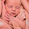 baby, newborn, sleeping, pink_blanket, soft_texture, hand, face, peaceful, wrapped, infant, portrait, closeup, skin, cute, resting, child, warm, cozy, patterned_fabric, toddler