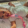 baby, infant, smiling, pacifier, blanket, zebra_pattern, onesie, curly_hair, dimples, sunlight, shadow, hand, face, mouth_open, lying_down, cute, child, indoor, fabric, pink