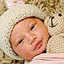 baby, infant, knitted_hat, pink_bow, crocheted_toy, teddy_bear, blanket, soft_texture, sleepy, closeup, cute, child, face, newborn, cozy, warm, wrapped, portrait, indoor, comfort